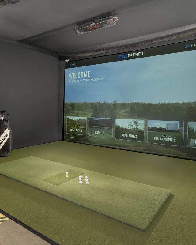 The hitting mat in a bay, balls waiting and the simulator screen lit.