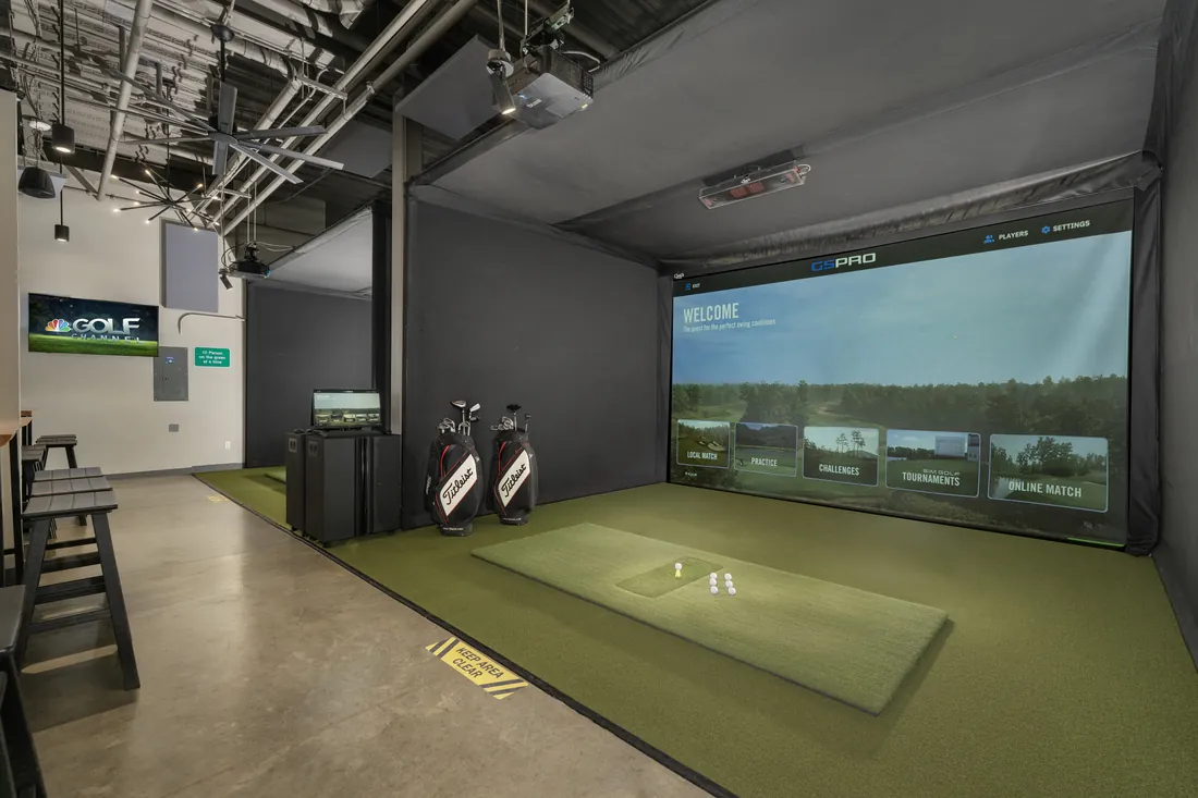 A bay ready to go: clubs by the wall, balls on the mat, the screen lit.