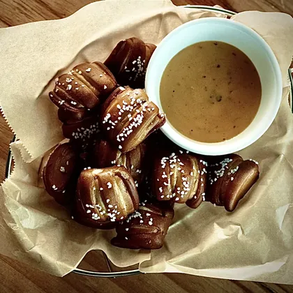 Pretzel bites in a paper-lined basket with queso for dipping.