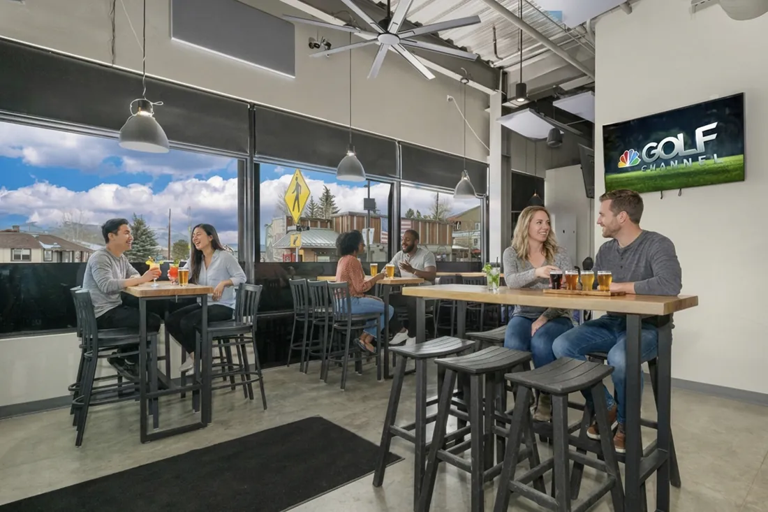 Friends sharing a beer flight at a high top by the front windows.